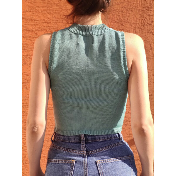The backside of a model wearing Collage No.1 knit west, in the outdoors on a sunny day.