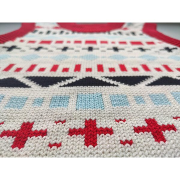 A close up shot of a fair isle knit t-vest, focusing on details on the front, the fair isle shapes including a plus symbol, squares, straight lines and triangles.