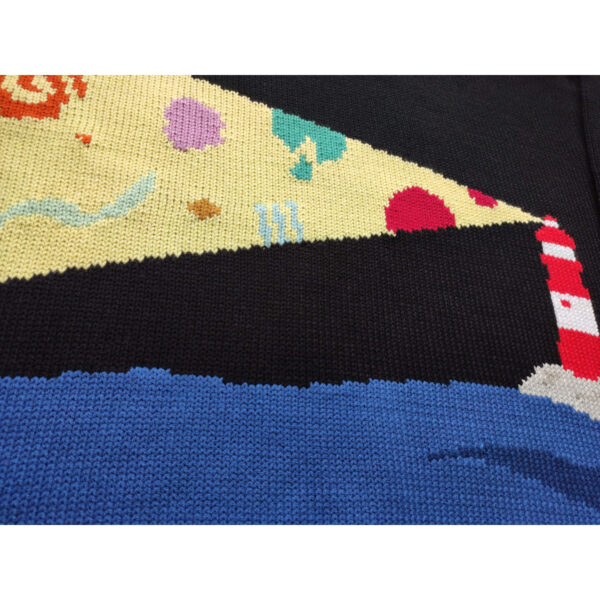 A close up shot of the knitted lighthouse with colourful shapes and the night sky, in the sea.