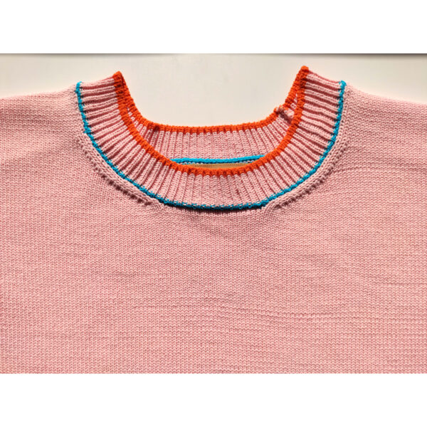 A close up shot of a surfing ghost themed pink knit t-shirt, focusing on the neck band