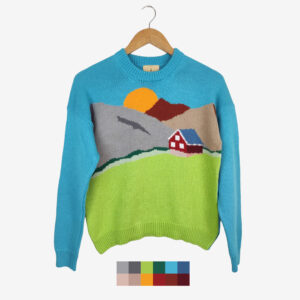 The catalogue shot of the intarsia landscape sweater, which features a house by the mountains and the sun, coloured green, blue, shades of brown, red and white.