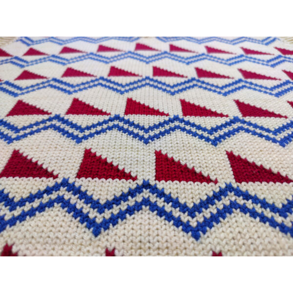 A close up shot of a fair isle knit vest, featuring the colours beige, red and blue.