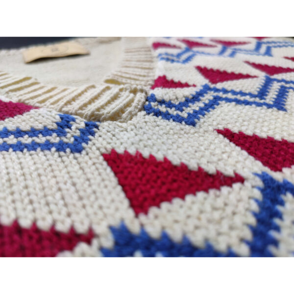 A close up shot of a fair isle knit vest, featuring the colours beige, red and blue, focusing on the V neck.