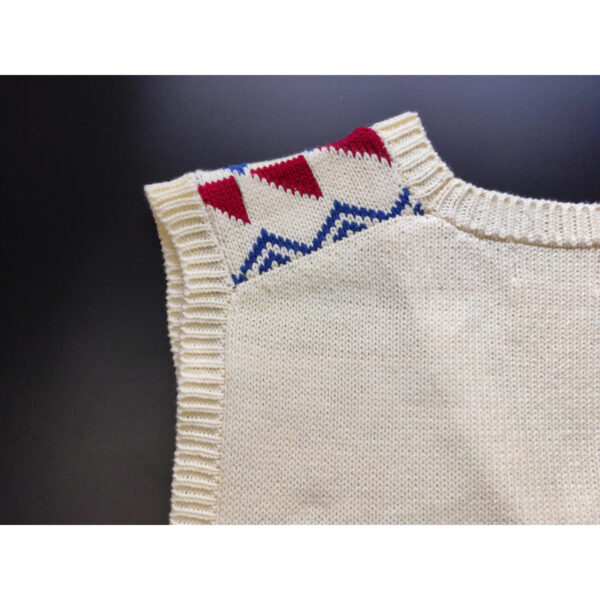 A close up shot of a fair isle knit vest, featuring the colours beige, red and blue, focusing on the back side and the nape.