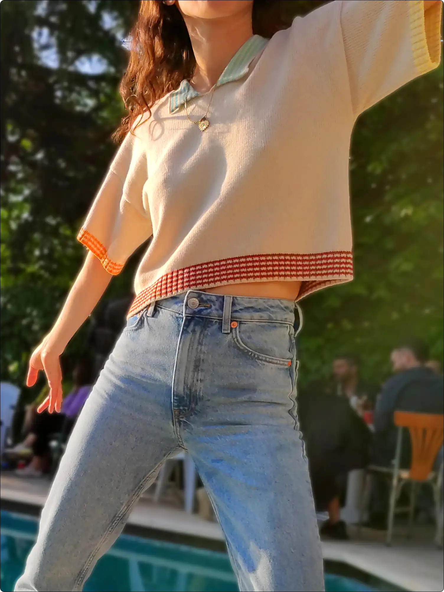 A young woman standing by the pool wearing a minimalistic designed knitting t-shirt.