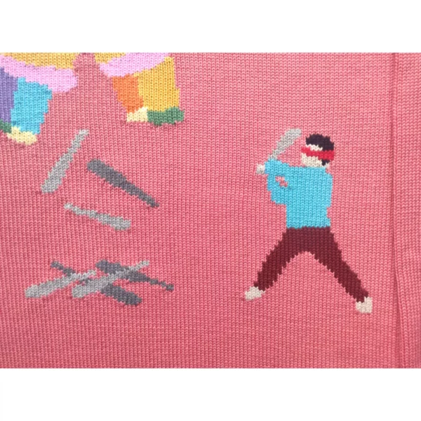 A close up shot of the handmade sweater featuring a kid wielding a baseball bat as he strikes a piñata, which, notably, is filled with more baseball bats.